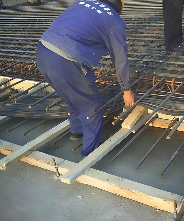 Construction workers placing waterstop strips between wooden boards and rebar